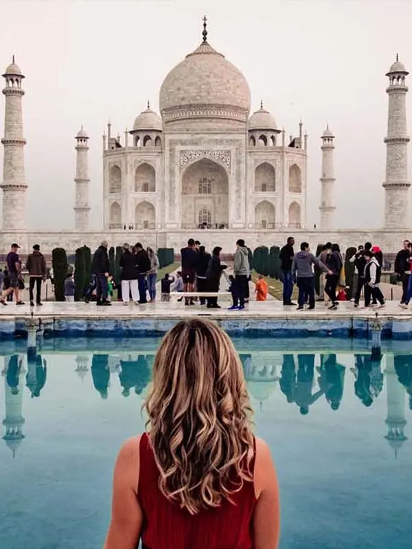 Female tourist enjoying a Taj Mahal sunrise tour in Agra India with iconic monument reflection view